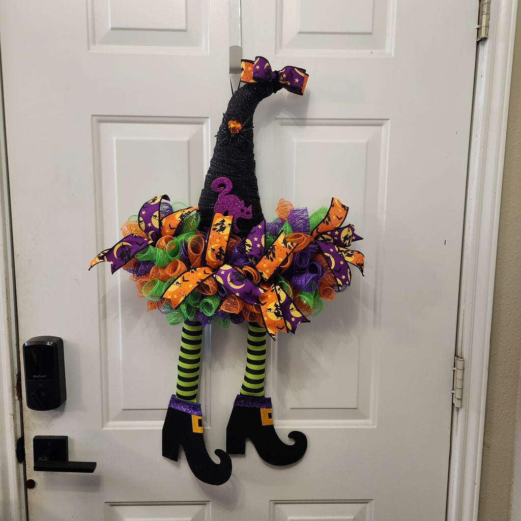 Witch Hat Halloween Deco Mesh Wreath on front door with dangling witch legs and curly boots