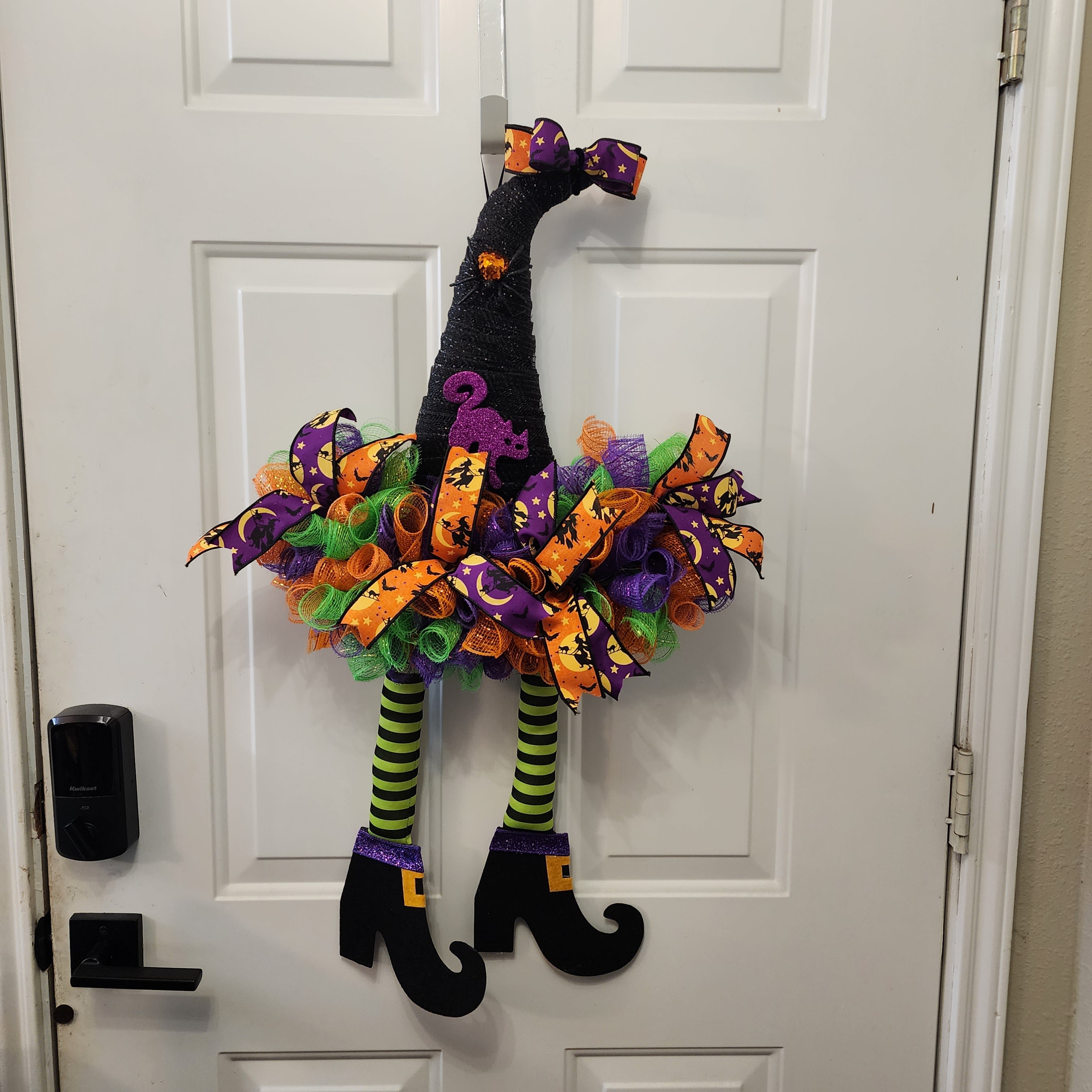 Witch Hat Halloween Deco Mesh Wreath on front door with dangling witch legs and curly boots