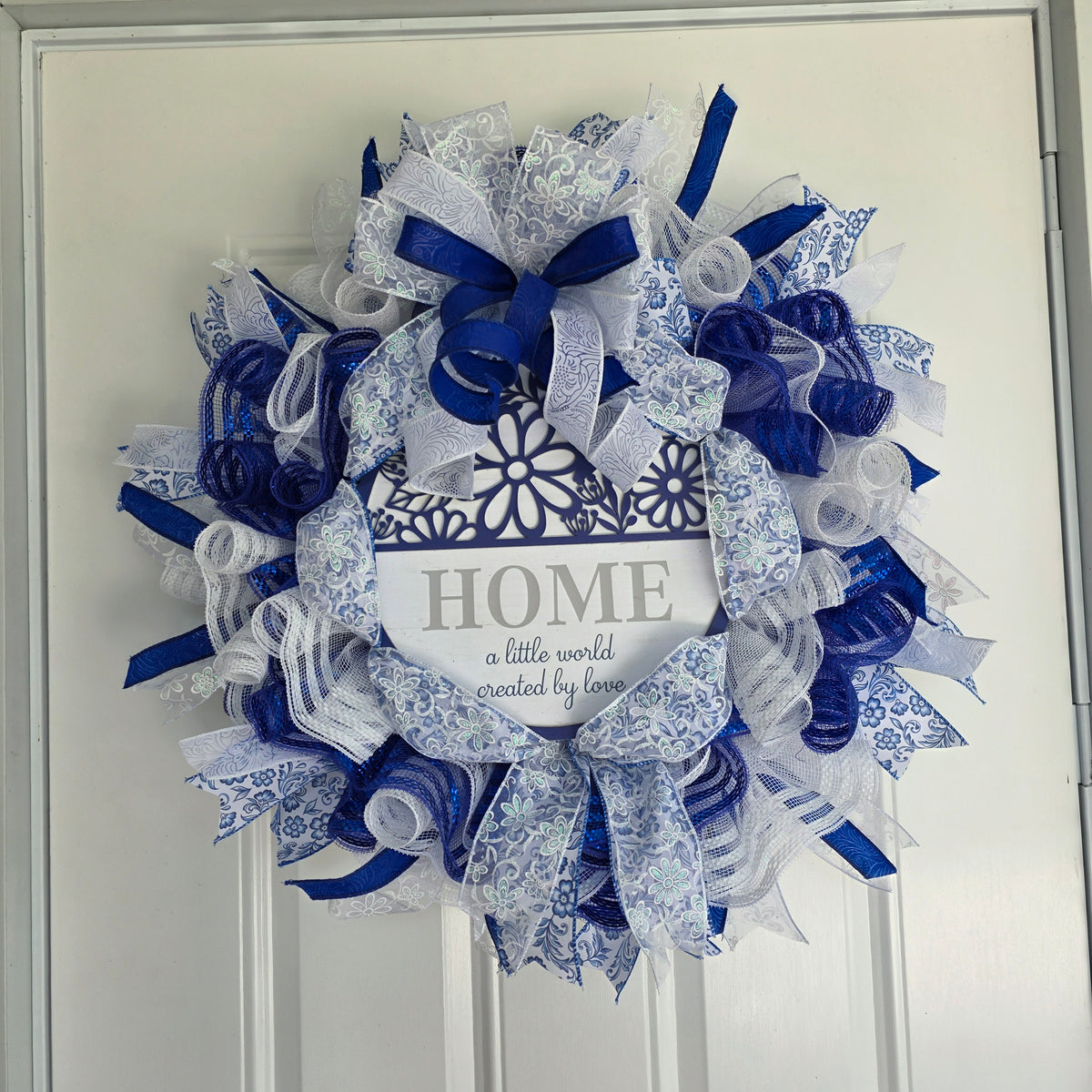 Home A Little World Created By Love Blue White Wreath - angle view on white door