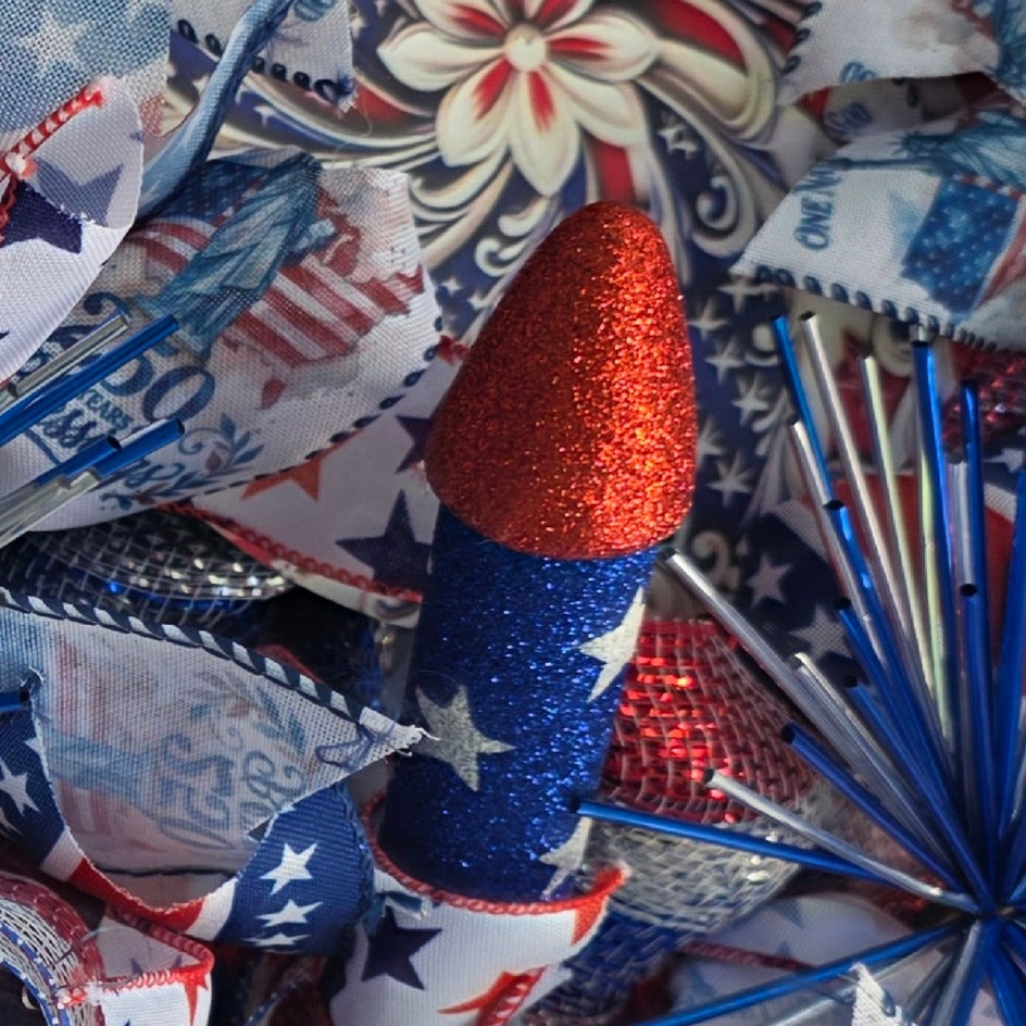 Close-up of blue glitter firework rocket pick with star ribbon
